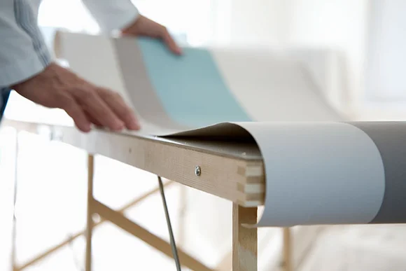 Person breitet Tapete auf Tisch aus